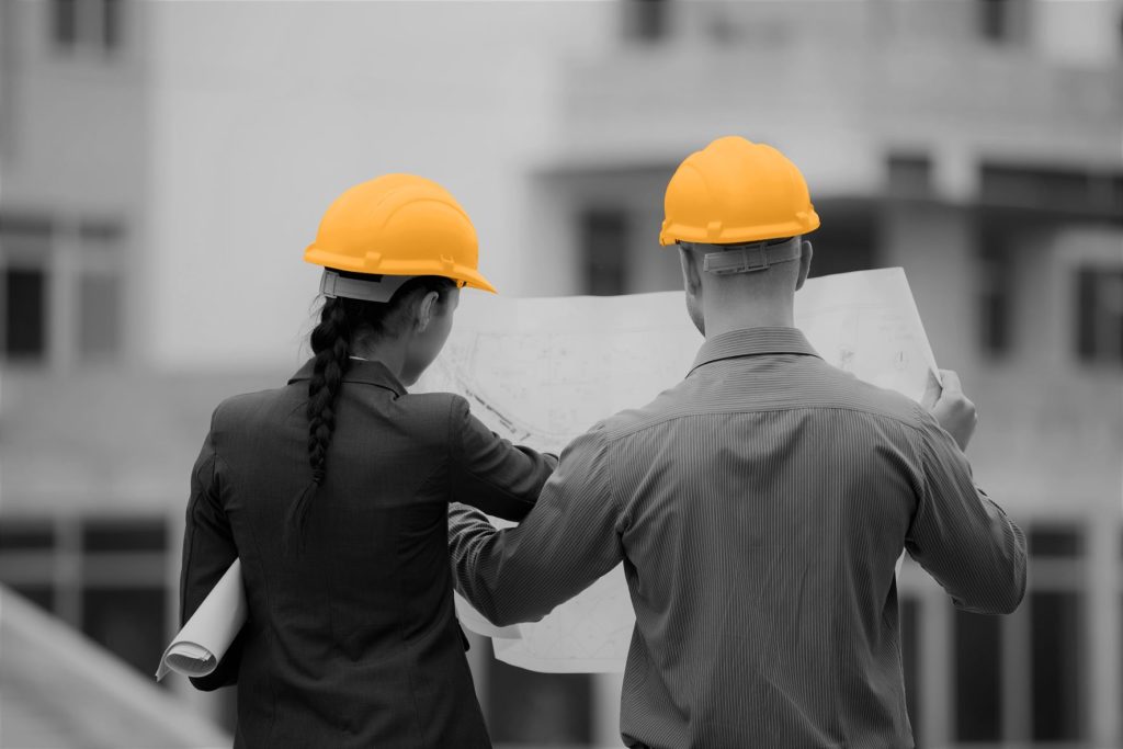 Image depicting one of Provelio services - project programme and portfolio management. One man and one woman stood with their backs facing the camera, looking at a scheme of works.