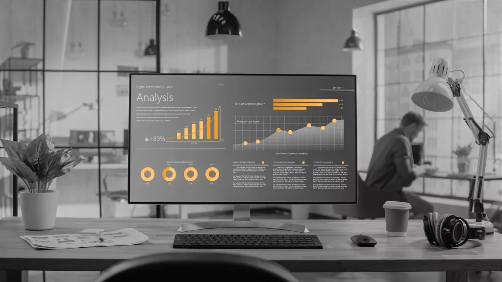 Image depicting Provelio services - Data and Estates Visualisation. Black and white image of a computer screen set to the backdrop of an office, with various graphs.